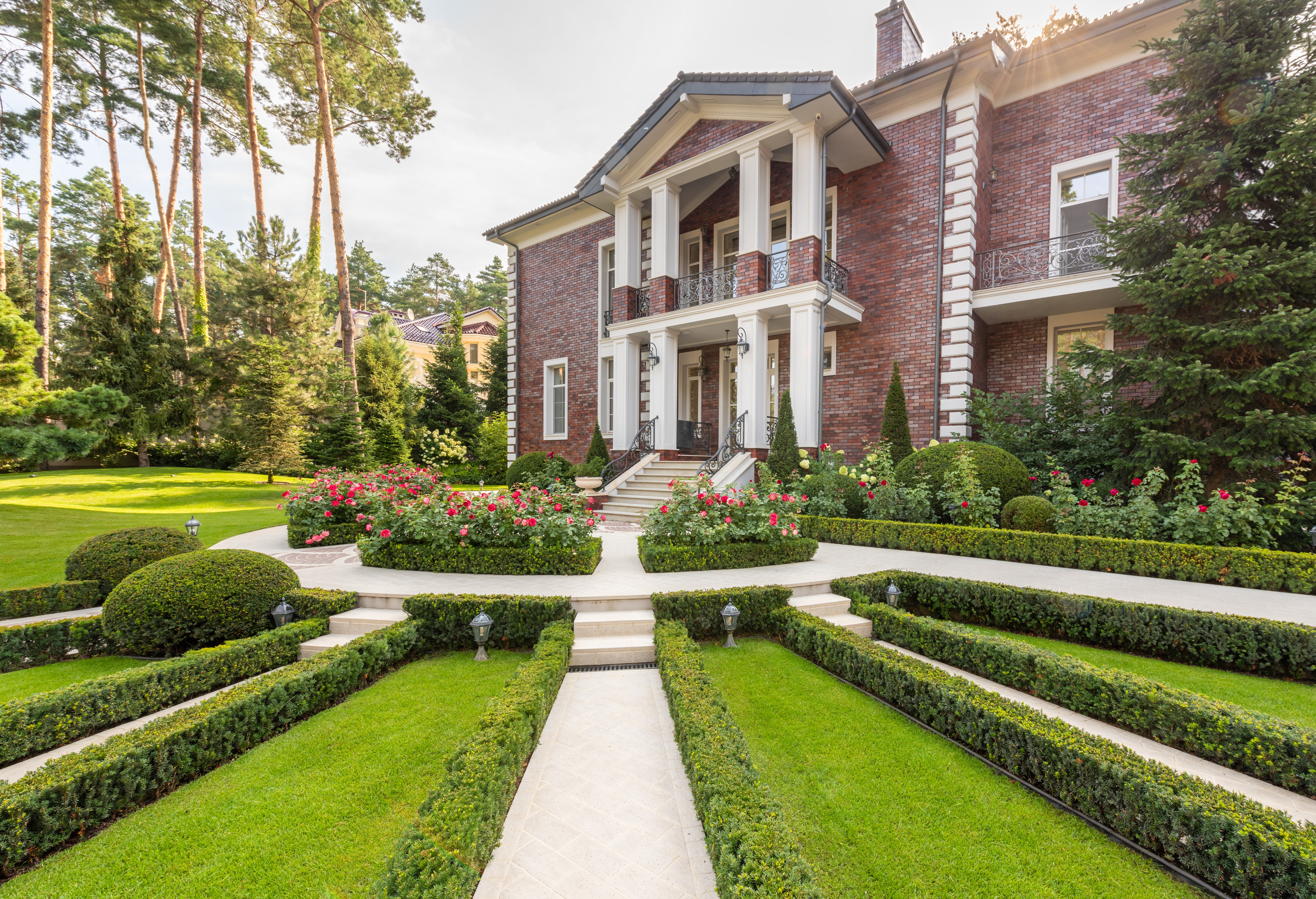 Large classic home with white pillars and landscaped front yard with flowers and hedge trimming services